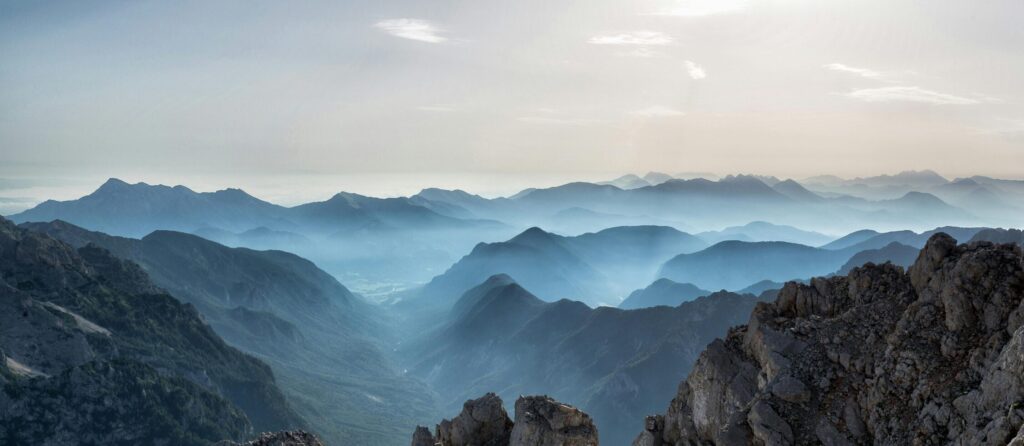 Capture of a tranquil mountain range at dawn with misty valleys and rocky peaks.